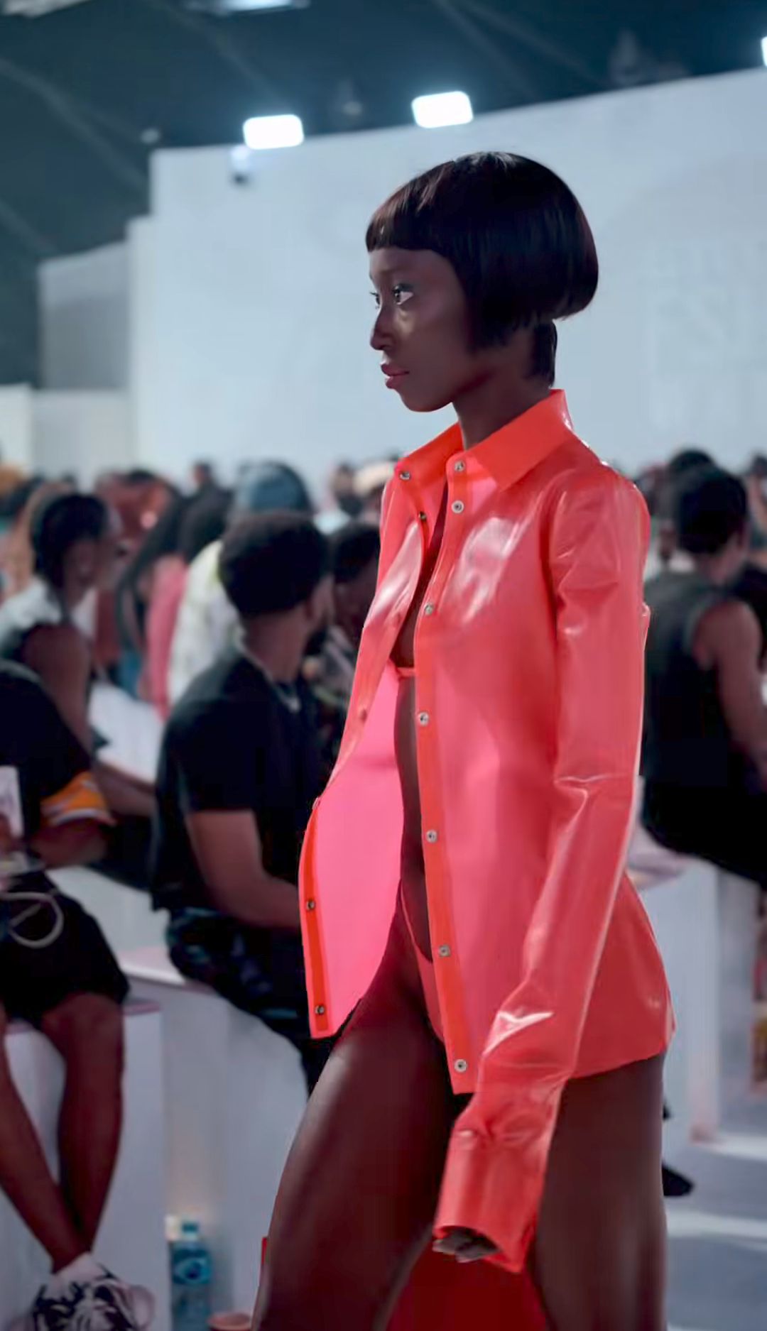 Side runway view of the glossy shirt and low-rise shorts