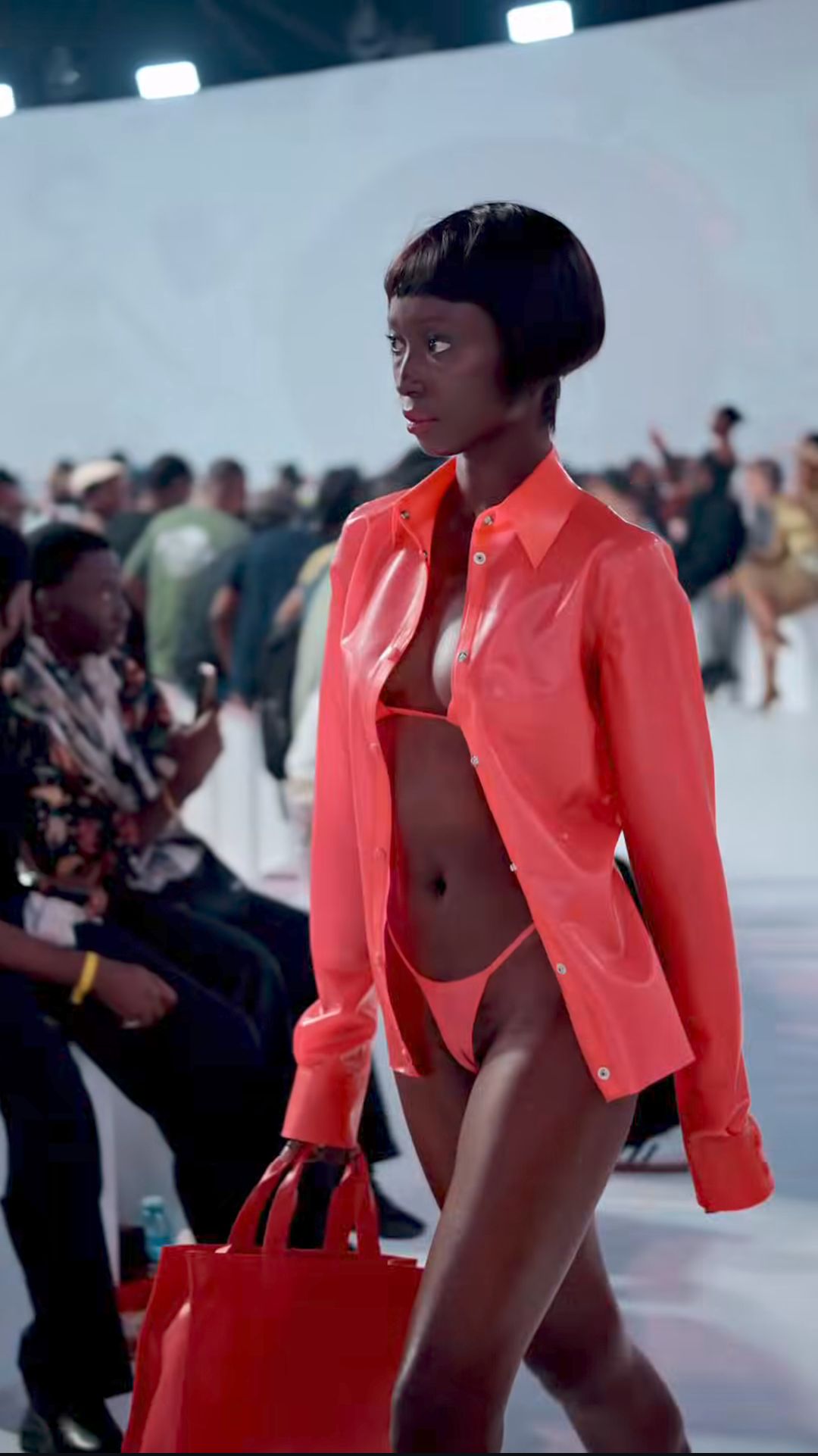 Front runway view of the glossy pink-red shirt and bag