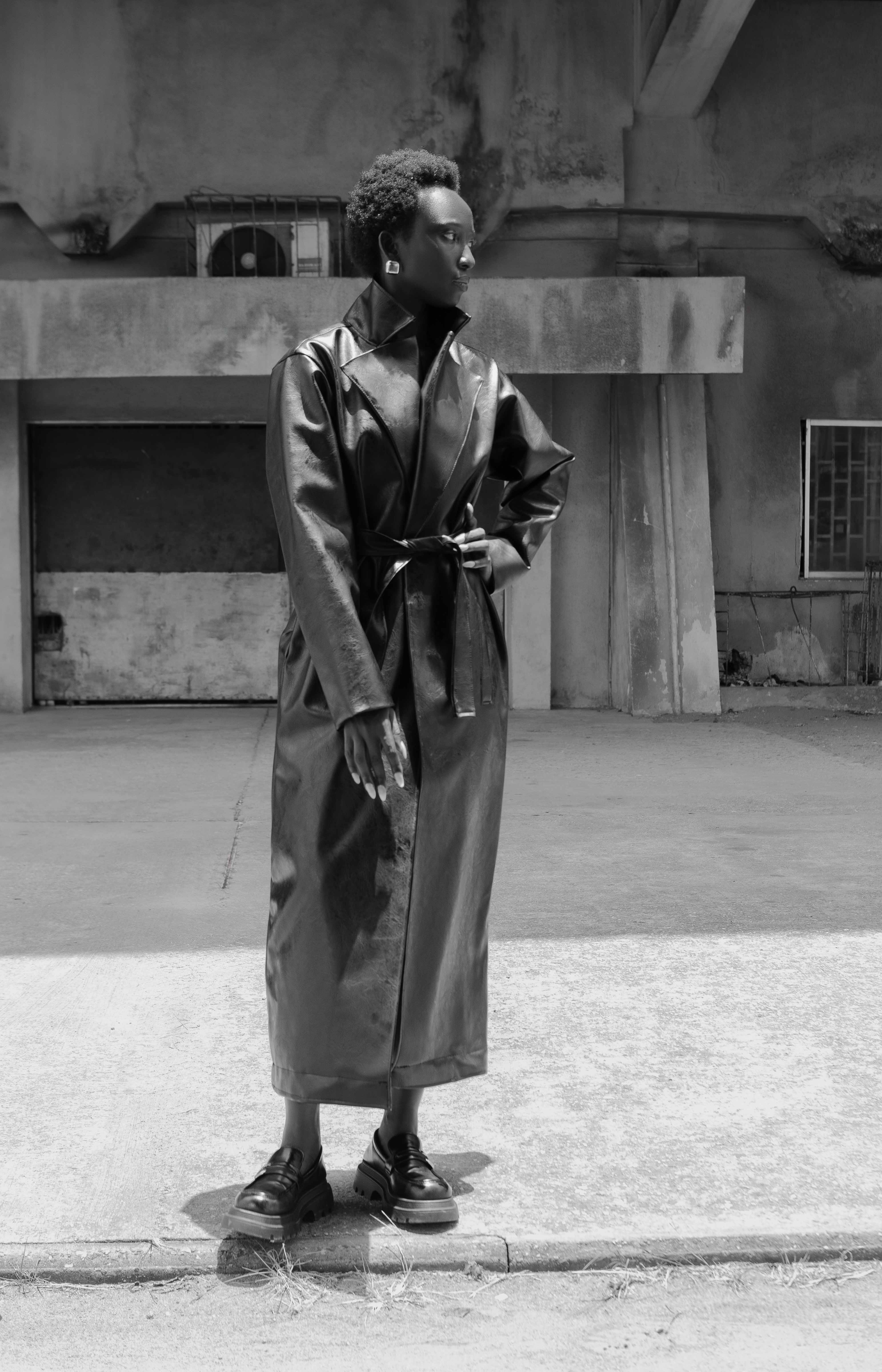 Full-length black-and-white coat portrait against concrete